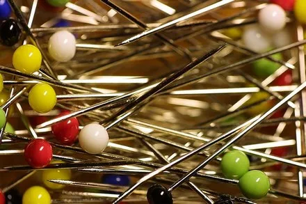 A close-up jumble of dressmaking pins with coloured heads.